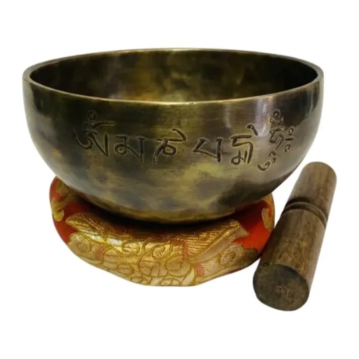 A hand-hammered bronze singing bowl densely etched with mantra script, viewed from above