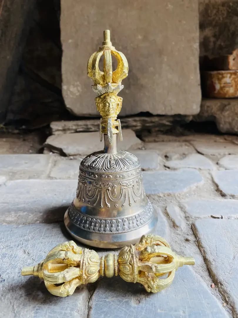 A hand-cast bronze bell and bajra resting on a stone doorstep in Patan