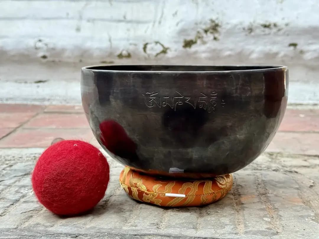 A hand-hammered singing bowl and mallet resting on stone steps